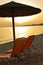 Two orange chairs and stray parasols on a beach at sunset, west coast of Sithonia
