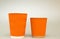 Two orange grooved paper cups for coffee stand on a white background, large and small