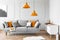Two orange lamps above grey scandinavian couch with pillows