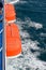 Two orange life boats on a ferry on sea