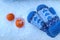 Two orange mandarins, blue mittens lying on the snow, top view, close - up-the concept of the arrival of bright winter days