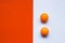 Two orange ping pong balls on an orange and white background.