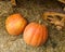 Two orange pumpkins lie on the straw by the cart wheels on the ground