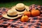 two orange pumpkins and a straw hat on a picnic blanket