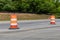 Two orange and white traffic barrels dividing a rural street in a road construction zone, copy space