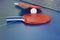 Two paddle, tennis ball on blue ping pong table