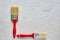 Two paintbrushes with red handles on freshly made concrete background. Repairing concept. Top view with copy space