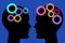 Two painted silhouette heads facing each other with colorful gears isolated on blue background. Think and communication concept.