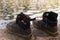 Two pair of boys shoes standing on the stone of a lake while they are having fun swimming