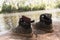 Two pair of boys shoes standing on the stone of a lake while they are having fun swimming