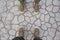 Two pair of feet on a dried crust in Dead Vlei, top view. Canvas hiking shoes standing on the ground, top view.