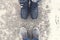 Two pair of legs wearing winter shoes stand opposite each other on snowy road