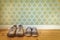 Two pair of old dirty shoes in front of retro wallpaper