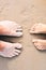 Two pairs of feet - a child and an adult - on a golden sandy beach. Vacation concept.