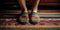 Two pairs of feet, one wearing rainbow-striped socks and the other in multicolored sandals, standing side by side on a