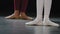 Two pairs of female legs on floor on performance stage in dance class studio do ballet exercises stretching the feet
