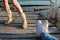 Two pairs of female legs on the wooden pier by the river. One girl in rolled-up blue jeans and white sneakers, another one in cowb