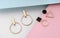 Two pairs of geometric shape golden earrings on pastel colors background