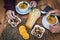 Two pairs of human hands take white bowls with pumpkin cream for healthy and vegetarian eating. Rustic and recycled wood table