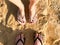 Two pairs of male and female legs with a manicure in slippers, a foot with fingers in flip-flops on a stone sandy floor, earth, be