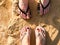 Two pairs of male and female legs with a manicure in slippers, a foot with fingers in flip-flops on a stone sandy floor, earth, be