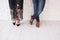 Two pairs of male and female legs in shoes are crossed. Couple standing in front of the white wall crossed-legs in shoes. Girl in