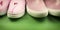Two pairs of pink shoes on a green background