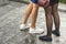 Two pairs of slim girls legs in short skirts, white leather sneakers and comfortable summer shoes on low platform. Fashion, style