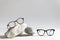 Two pairs of trendy glasses in plastic frame on stones on light background. Glasses sale poster. Optic store sale-out offer. Copy