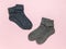 Two pairs of warm knitted socks on a light pink background. Minimal footwear concept