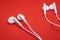 Two pairs of white earphones for listening music on red background - Image