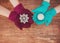 Two pairs of women hands knitted mittens holding a Christmas toy on a wooden background.