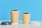 Two paper coffee cups with coffee beans on blue background