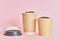 Two paper coffee cups with coffee beans on pink background