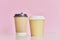 Two paper coffee cups on pink background. Creative mockup image