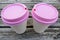 Two paper coffee cups with pink lids on wooden table