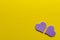 Two paper purple hearts on yellow background