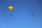 Two parachutes in blue clear sky on multi-colored parachutes