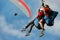 Two paraglider tandem fly against the blue sky