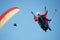 Two paraglider tandem fly against the blue sky