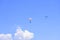 Two paratroopers descend against a blue sky