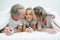 Two parents lying on the bed while kissing their daughter under a blanket