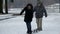 Two parents are walking on large skis without any hassle