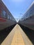 Two passenger cars stand on the tracks near one platform on a sunny day. Railway transport