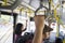 Two passengers hold handles on Transjakarta bus