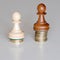 Two pawns chess pieces on columns of coins, symbolizing significant income inequality