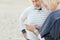 Two pensioners serfing by smartphone on sand beach.