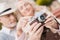 Two pensioners are sitting on the bench and studying a vintage camera. They are going to take a few photos