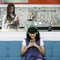 Two people, daughter playing and looking at smartphone while mother cooking food for her