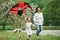 Two people and dog. Positive female child and grandmother running with red and black colored kite in hands outdoors